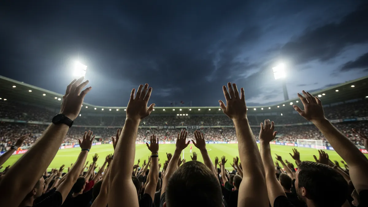 Manos levantadas de aficionados en las gradas de la Premier League al atardecer.